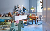Pastel blue, spacious child's bedroom with cheerful wooden toys and collection of soft toys