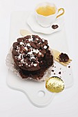 A chocolate cupcake decorated with sugar pearls with a bite taken out