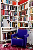 Royal blue armchair and standard lamp in front of bookcases