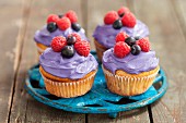 Cupcakes decorated with berry cream and fresh berries on a saucer