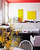 Lounge area with round coffee table and white sofa in front of wall with yellow artworks above sideboard