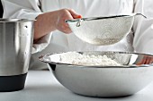 Flour being sifted into a large mixing bowl