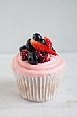 A strawberry and rhubarb cupcake with pomegranate seeds