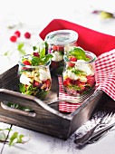 Jars of raspberries with mozzarella and basil on a wooden tray