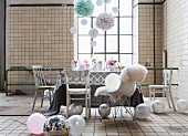 Listed industrial interior used as party location with delicate, romantic furnishings and decorated with balloons and paper pompoms