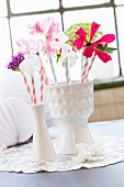 Summer flowers and drinking straws in two white china vases