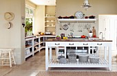 White island counter in open-plan, country-house kitchen with sand-coloured walls