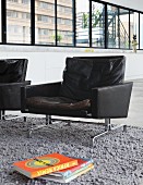 Black retro leather armchairs on grey, long-pile rug in designer loft apartment