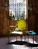 Yellow chair with panama hat and side table in room with wood paneling