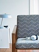Armchair with black and white upholstery and table lamp on white side table