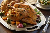 Two roast chickens with lemon, olives, onions and herbs