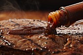 Steak sauce being poured onto a grilled steak