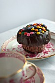 A cupcake with chocolate glaze and chocolate beans