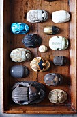 Various artistic carvings of scarab beetles arranged in vintage wooden crate