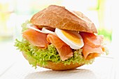 A bread roll filled with smoked salmon, egg and onions