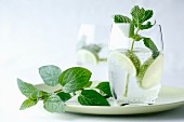 Fresh mint in a glass of water with limes on a green plate