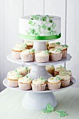 Vanilla cupcakes and a wedding cake decorated with green butterflies and sugar flowers on a cake stand
