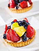 A fruit tart topped with strawberries, pineapples, blueberries and grapes