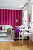 Sitzecke in skandinavischem Wohnzimmer mit weissen Möbeln vor rot-pink gestreifter Tapete