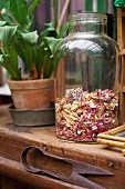 Dried petals in old glass jar on wooden surface