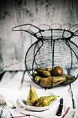 An arrangement of pears and a wire basket