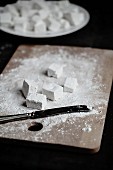 Homemade marshmallows dusted with icing sugar on a chopping board and in a bowl