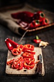 Sliced red pointed peppers on a board with a knife