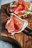 Parma ham with a fork on a wooden board
