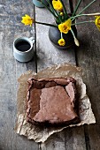 A slab of chocolate brownie with a cup of coffee