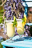Two mango and buttermilk shakes on a garden table