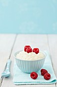 A bowl of rice pudding with raspberries