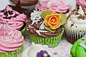Various cupcakes with sugar flowers, chocolate stars and grated chocolate