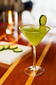 A cocktail garnished with a slice of cucumber