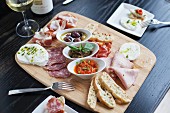 An antipasti platter with salami, Parma ham, mozzarella, spreads, olives and white bread