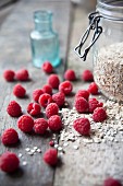 Frische Himbeeren und ein Glas Haferflocken auf Holztisch