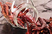 Dried chilli peppers spilling from an overturned storage jar