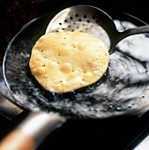 A poppadom being fried in a pan