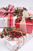 Wrapped Christmas gifts decorated with ribbons, rosehips and cinnamon sticks