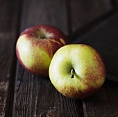 Two apples on a rustic wooden surface