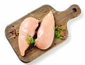 Two raw chicken breasts on a chopping board