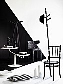 Künstlerisch veränderter Stuhl als Kleiderständer und weisser Beistelltisch vor schwarz-weisser, dreidimensional gestalteter Wand