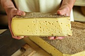 A dairyman presenting a slice of Vorarlberg Mountain Cheese
