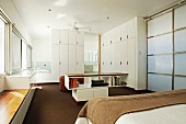 Modernes Schlafzimmer mit weissen Einbauschränken übereck und mittig ein halbhohes Medien-Regal