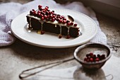 A slice of chocolate cake with cranberries and icing sugar