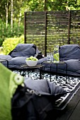 Set of side tables and black bean bags on black and white patterned rug in front of wooden screen