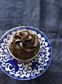 A chocolate cupcake on a blue and white saucer