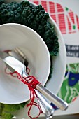 Cutlery wrapped in red yarn in white soup bowl