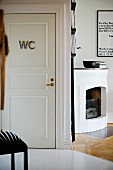 Open corner fireplace next to white interior door with WC sign