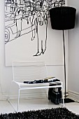 Delicate white Spaghetti Chair and black standard lamp in front of picture in corner