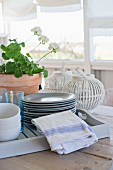 Tray of crockery and white slatted lantern on wooden table